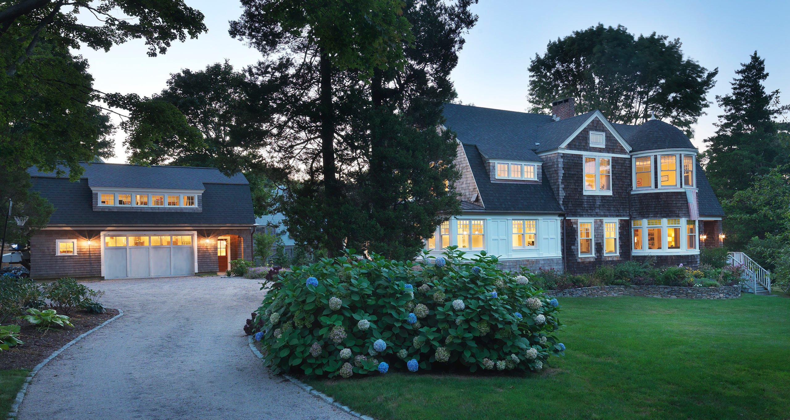Dusk view of gravel drive leading to carriage house with Captain's house on the right